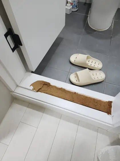 문지방 필름 — 윗면 필름이 벗겨져 속판이 드러난 문지방
